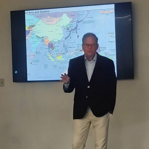 Charles Williams presenting beside a map of East Asia and Oceania